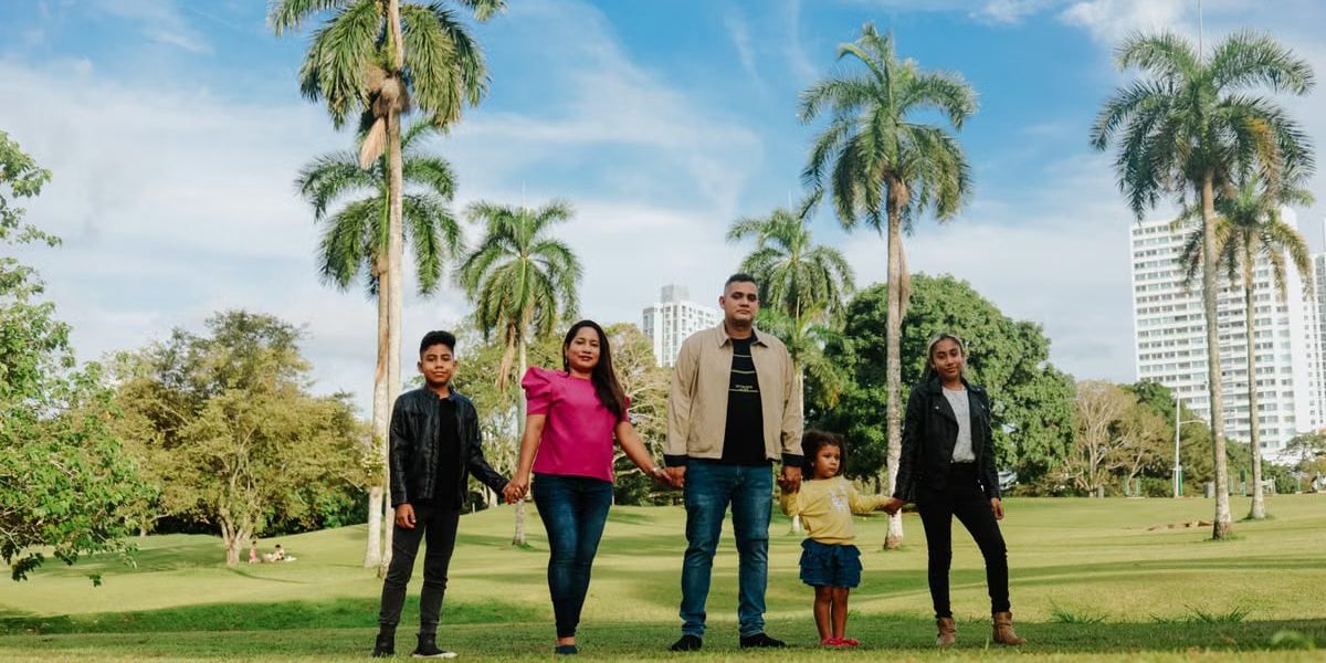 A cheerful family enjoys a sunny day in the park, surrounded by palm trees and lush greenery.
