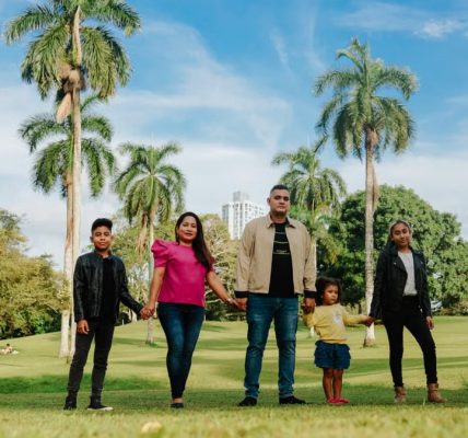 A cheerful family enjoys a sunny day in the park, surrounded by palm trees and lush greenery.