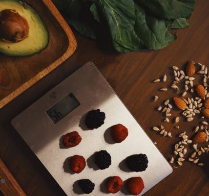 Top view of composed raw almond with seeds and avocado on table with berries on scales for cooking healthy dish